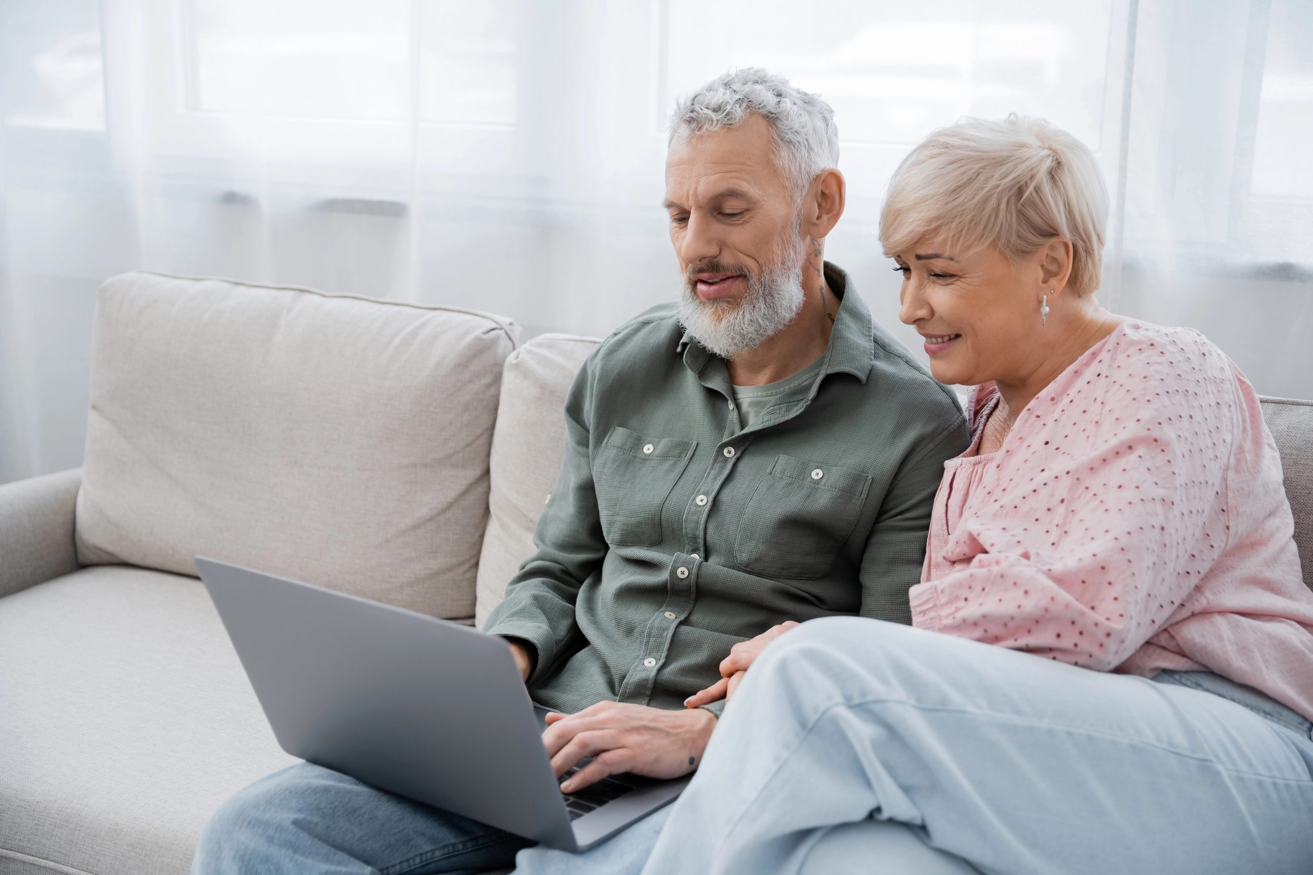 Senior couple at home reading content on a laptop together
